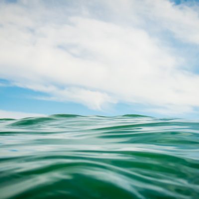 Close-up photograph of ocean wave against the blue sky