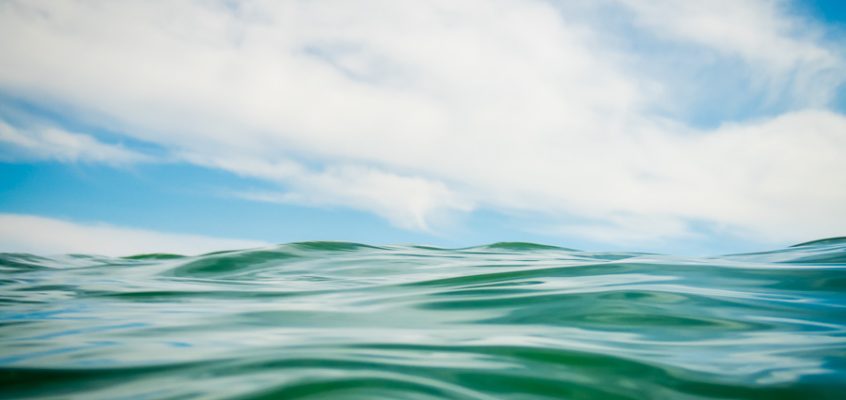 Close-up photograph of ocean wave against the blue sky